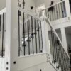 Side mount baluster bracket with black spindle on white painted wood stairs